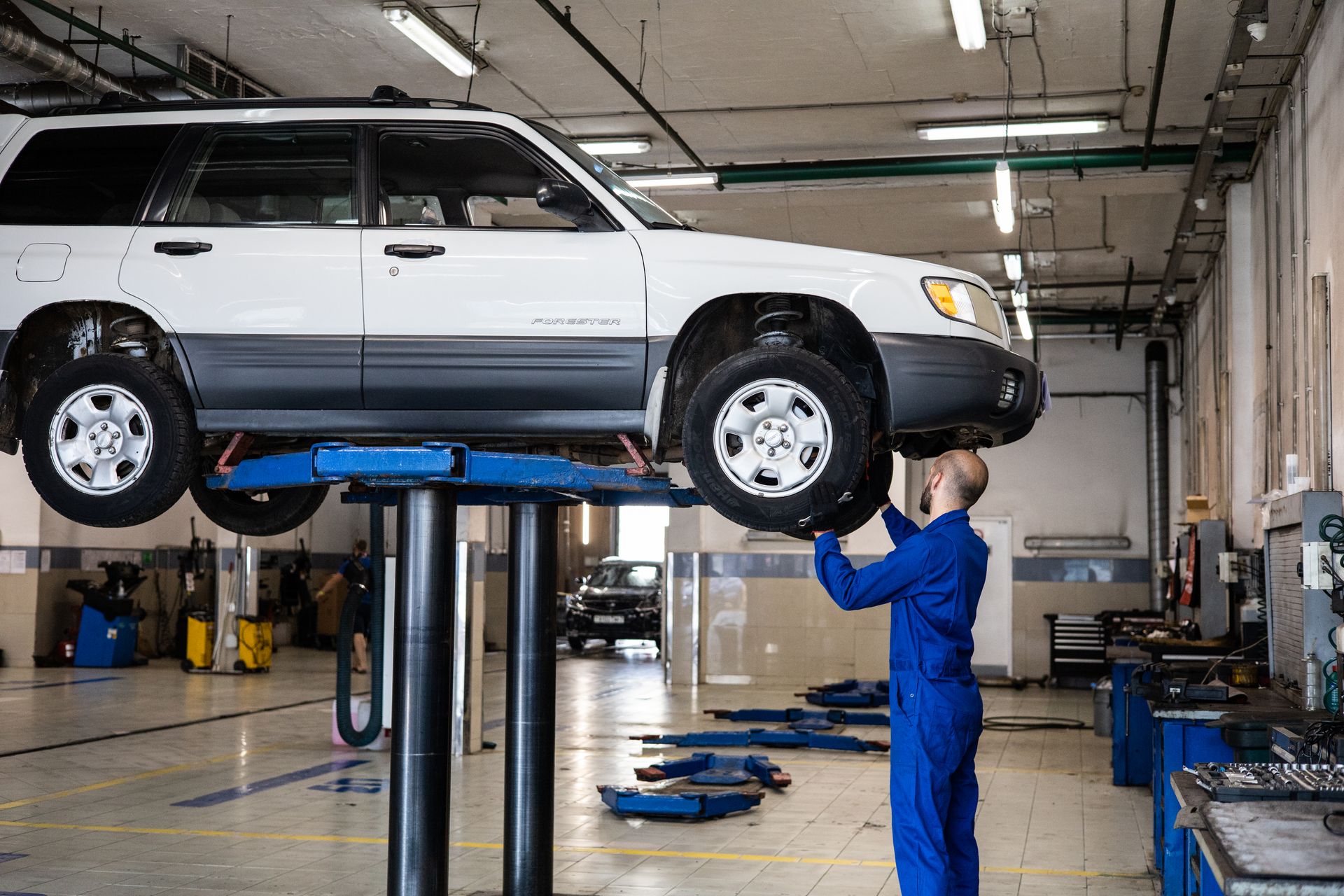 Modern performance workshop bay with a car on a hydraulic lift and epoxy floors